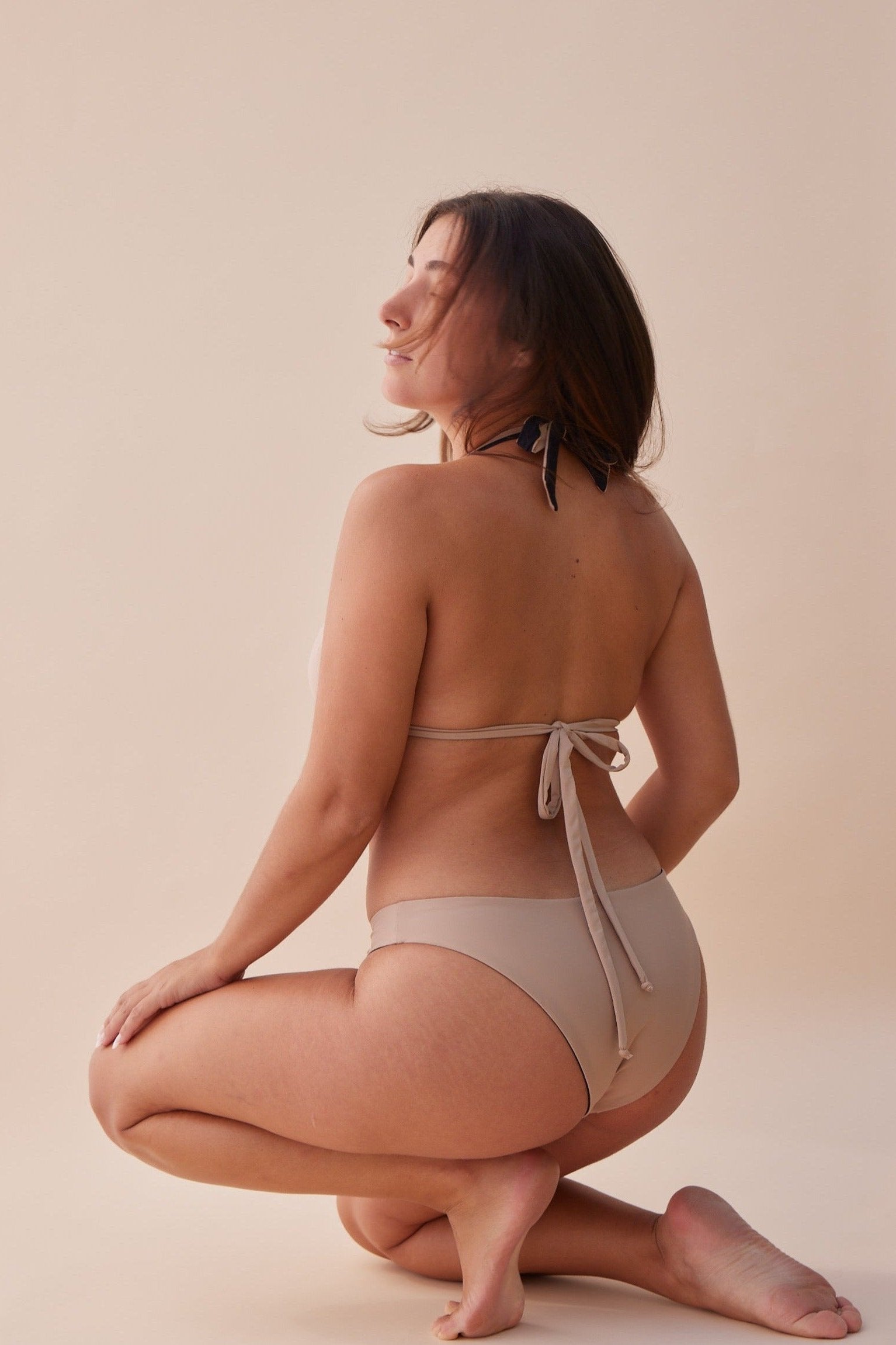 Back view of model wearing Reversible Koloa Mid Rise Bottom in dune color with tan style